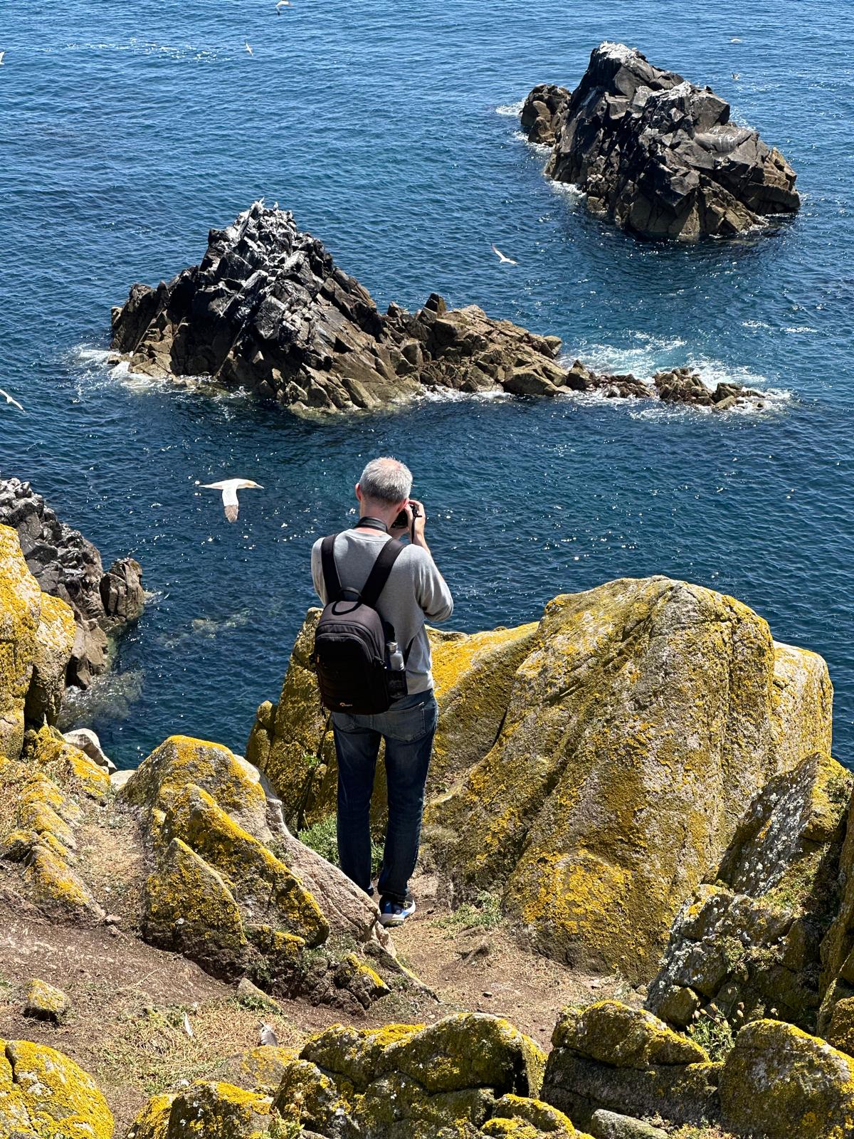 Paul Forde photographing on a cliff overlooking the Irish coast
